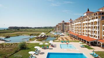 Un resort con múltiples piscinas, una piscina central amplia y vistas del paisaje circundante.