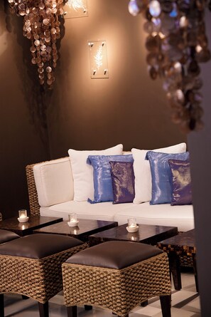 A modern lounge area with a sofa, two side tables, and a decorative wall piece. - Sunrise All Suites Resort (Nessebar)