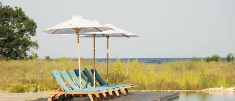 A poolside area with lounge chairs and umbrellas.