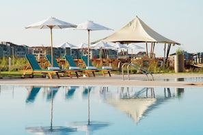 A poolside area with lounge chairs and umbrellas, a stone fountain, and a view of residential buildings in the background. - Sunrise All Suites Resort (Nessebar)