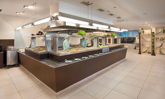 A buffet setup with multiple food stations, a clean tiled floor, and a modern kitchen hood above.