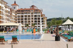 A hotel with a pool area, outdoor seating, and a large building with multiple balconies. - Sunrise All Suites Resort (Nessebar)