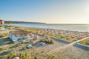 A beachside resort with thatched-roof huts, sun loungers, and a wooden boardwalk leading to the beach. - Sunrise All Suites Resort (Nessebar)
