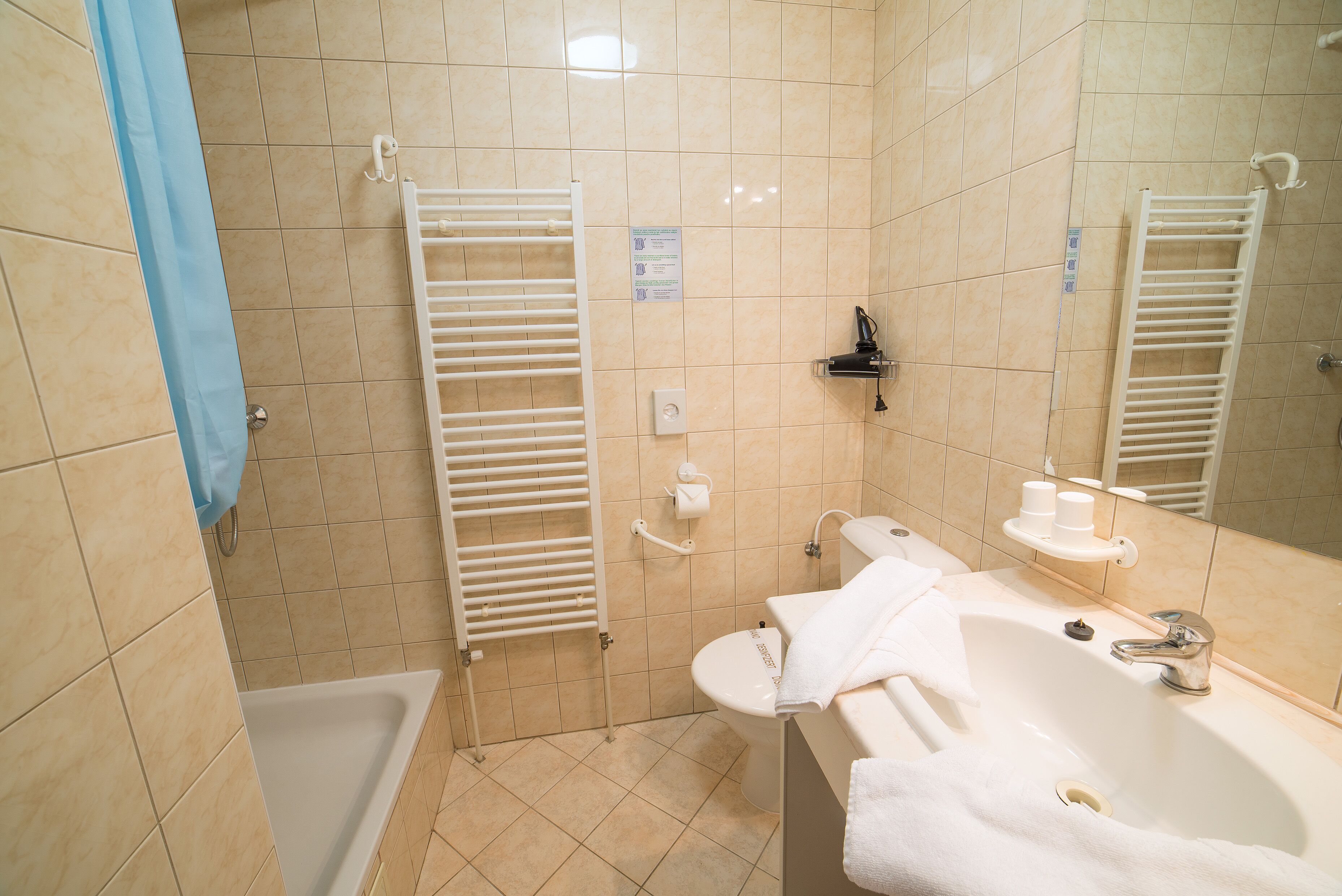 Un baño con bañera, lavamanos, espejo y toallero.