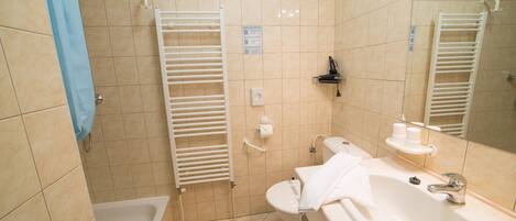 Un baño con bañera, lavamanos, espejo y toallero.