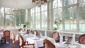 A dining area with tables set for service, large windows, and a chandelier. - Imperial Spa Hotel (Frantiskovy Lazne)