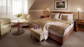 Una habitación de hotel con cama, una silla, una mesita y una lámpara.