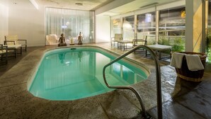A swimming pool with a clear water view, surrounded by seating areas and large windows. - UY Proa Sur Hotel (La Paloma)