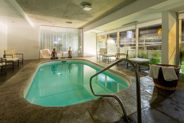 A swimming pool with a clear water view, surrounded by seating areas and large windows.