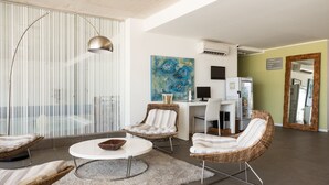 A modern living room with wicker furniture, a round coffee table, and a painting on the wall. - UY Proa Sur Hotel (La Paloma)