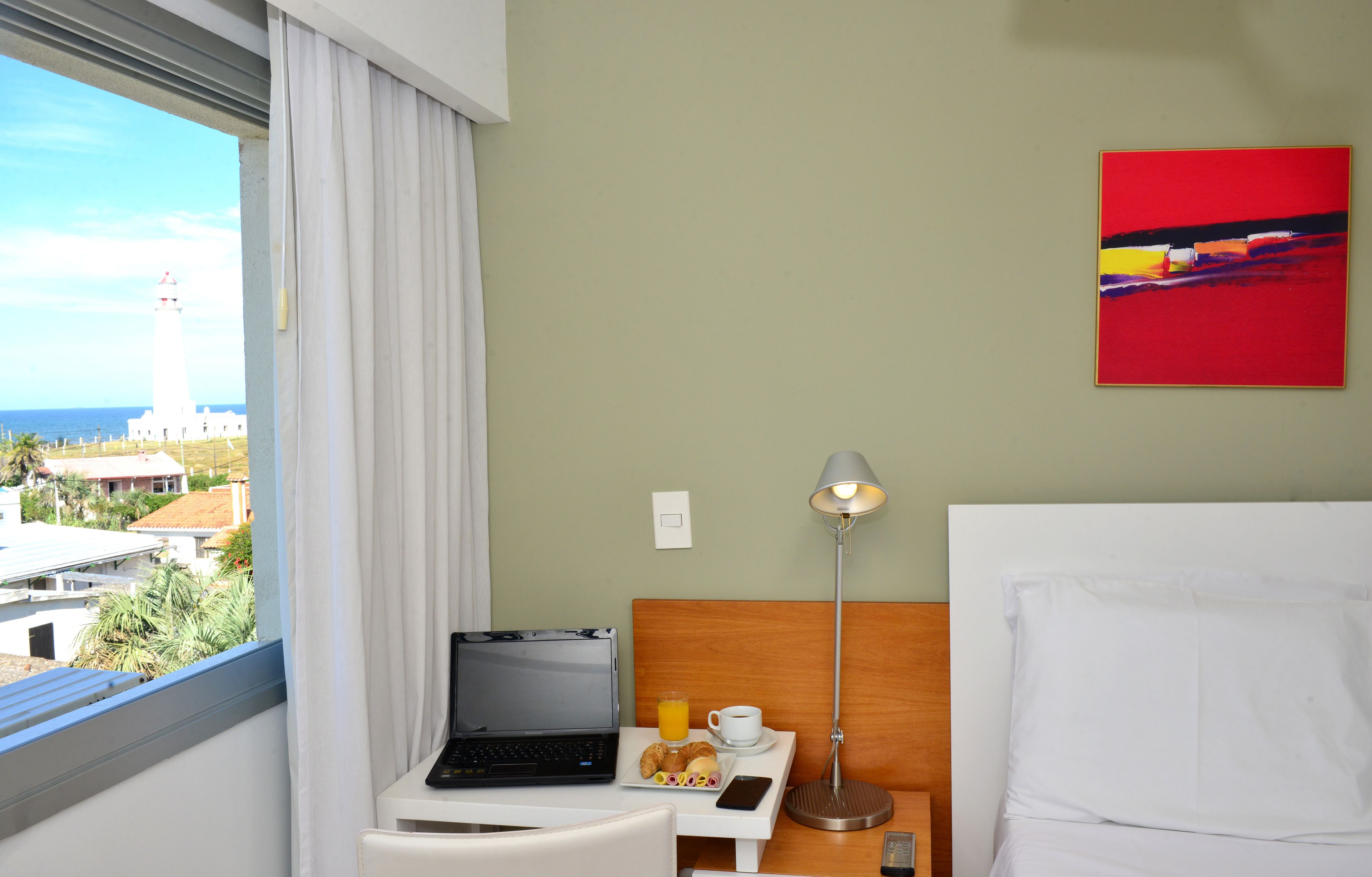 Habitación de hotel con una computadora portátil, bandeja de desayuno y una lámpara.
