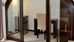 A hotel room with a bed, a desk, a chair, and a television mounted on the wall.
