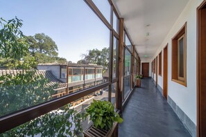 A corridor with large windows, wooden doors, and a view of traditional buildings and trees. - Guipu Courtyard Hotel (Beijing)
