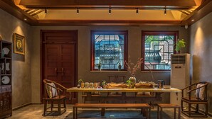 Un coin repas avec une table en bois, des bancs et une vue sur un bâtiment traditionnel, visible à travers une fenêtre.