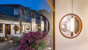 Un bâtiment moderne doté de grandes fenêtres, d’un patio avec des chaises et d’un luminaire suspendu.