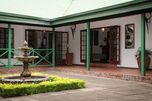 A courtyard with a fountain, green-framed doors, and a potted plant. - Tzaneen Country Lodge (Tzaneen)