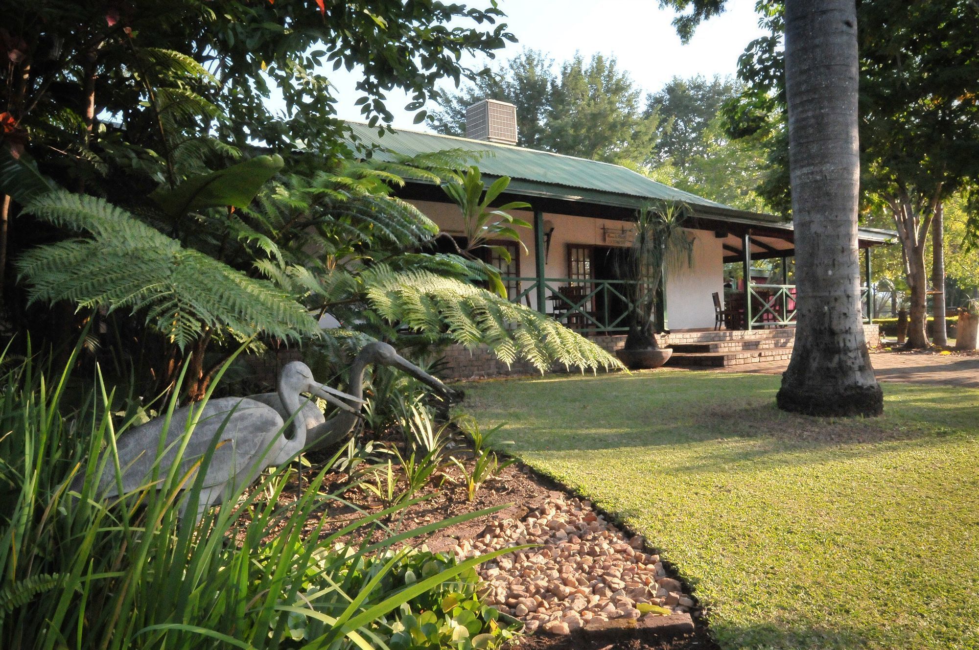 A building with a green roof, surrounded by lush greenery and a stone pathway.