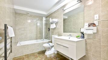 A modern bathroom with a bathtub, toilet, and vanity.