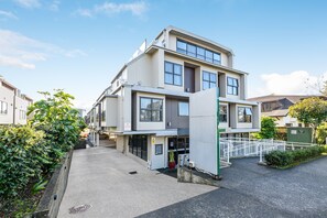 A modern multi-story building with a flat roof, large windows, and a gated entrance.