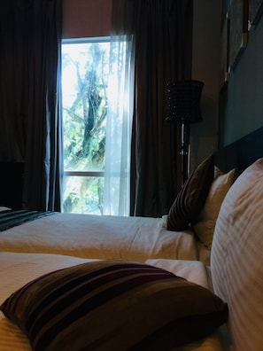 A hotel room with a bed, a window with curtains, and a lamp. - Orion Design Hotel (Kuala Lumpur)