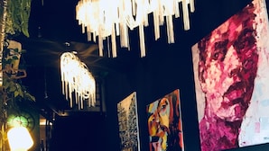 Un interior moderno con una pared oscura, una lámpara colgante y varias obras de arte.