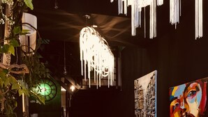 Un interior moderno con una barra de madera, sillones tapizados en terciopelo azul, un reloj de pared verde y arte abstracto.