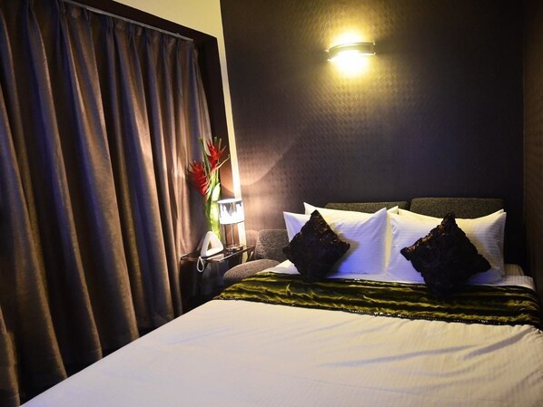 Une chambre d’hôtel avec un lit, une table de chevet, une lampe et un luminaire fixé au mur.