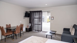 A modern living room with a dining area, a sofa, and a TV mounted on the wall. - 58 On Cron Motel (Franz Josef Glacier)