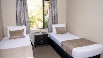 A twin room with two beds, a nightstand, and a window with curtains.