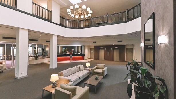 A spacious lobby with a high ceiling, a chandelier, a reception desk, and multiple seating areas. - Nesuto Pennant Hills (Pennant Hills)