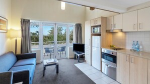 A modern kitchen with a flat-screen TV, a dining area with a table and chairs, and a sofa. - Nesuto Pennant Hills (Pennant Hills)