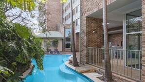 A swimming pool with lounge chairs, surrounded by brick buildings and greenery. - Nesuto Pennant Hills (Pennant Hills)