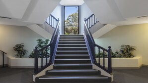 A staircase with a modern design, surrounded by potted plants. - Nesuto Pennant Hills (Pennant Hills)
