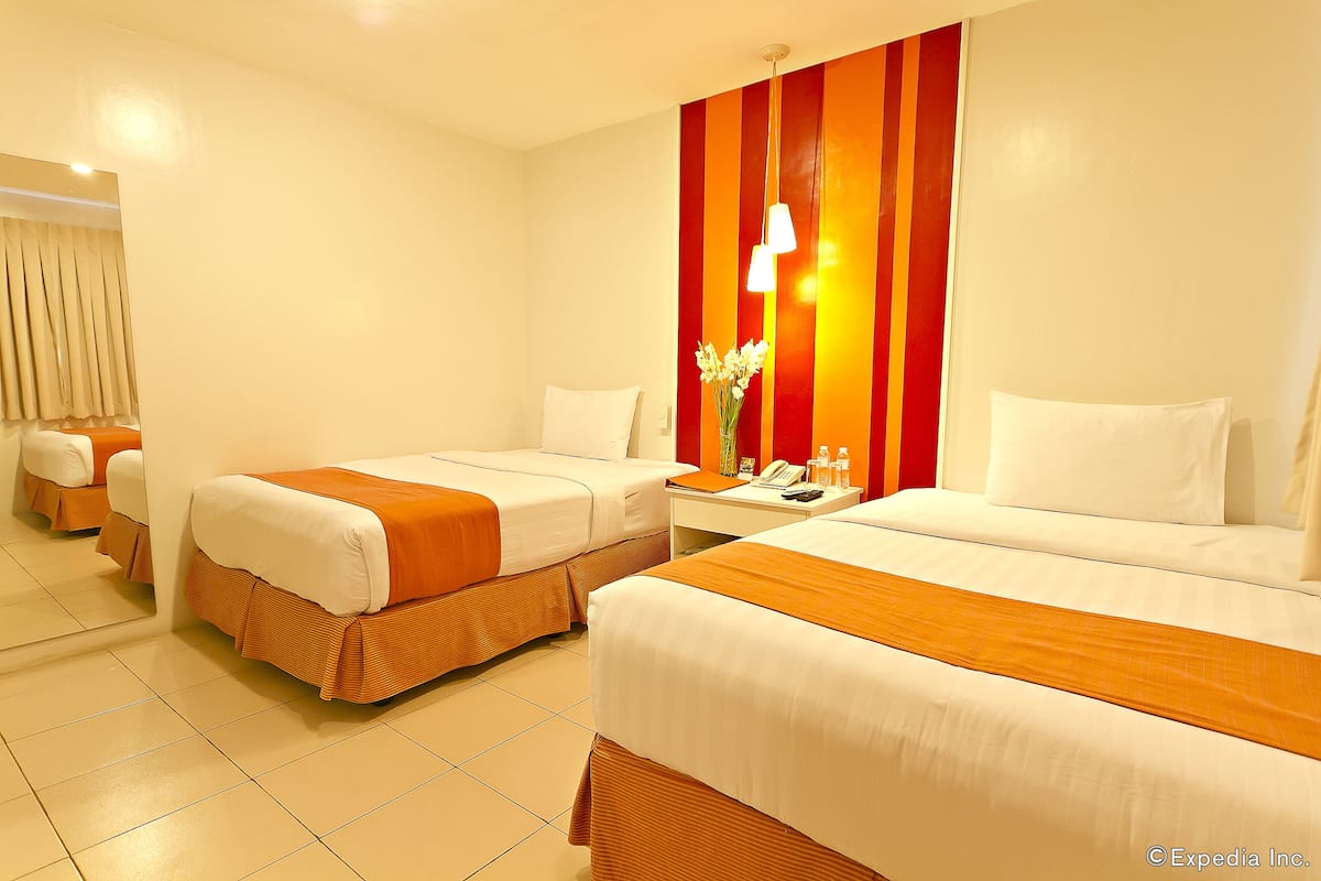 A hotel room with two beds, a nightstand, a telephone, and a vase with flowers.