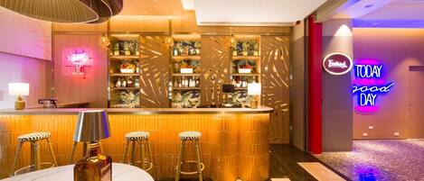 A bar area with a counter, stools, and a neon sign.