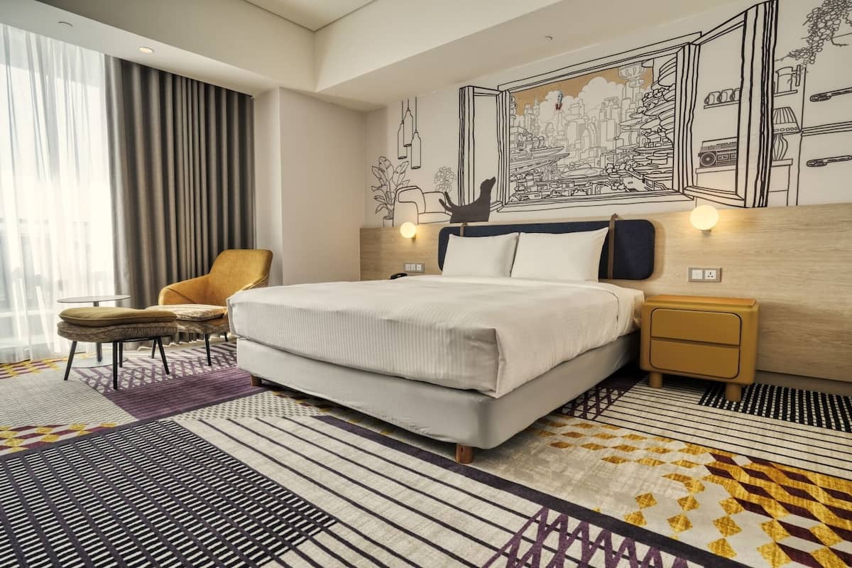 A modern hotel room with a large bed, a chair, a nightstand, and a wall mural.
