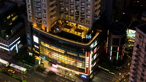 A high-rise hotel with multiple floors, a rooftop terrace, and illuminated signage.