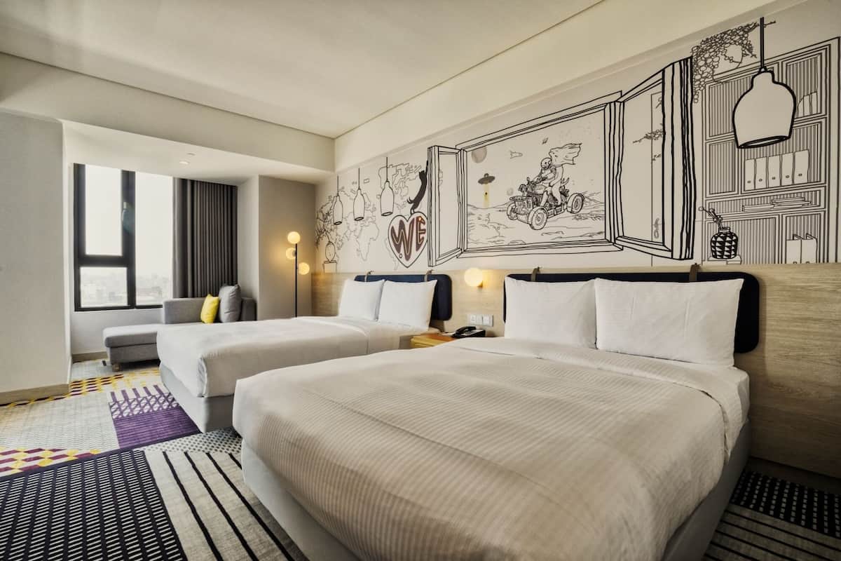 A hotel room with two beds, a large window, and a wall mural.