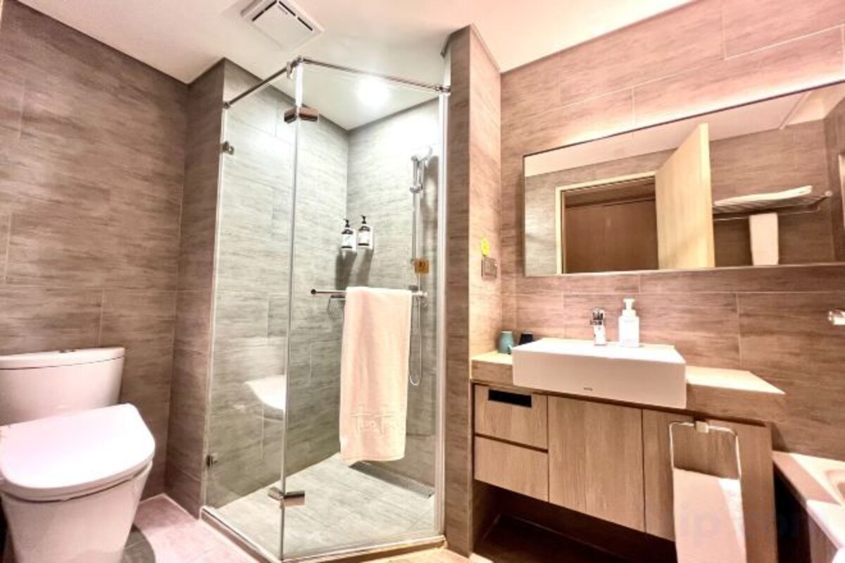 A modern bathroom with a glass-enclosed shower, a toilet, a sink, and a mirror.