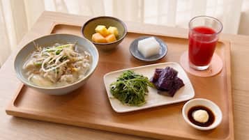 A tray with a bowl of soup, a plate of vegetables, a small dish of pickled vegetables, a bowl of fruit, and a glass of red drink.