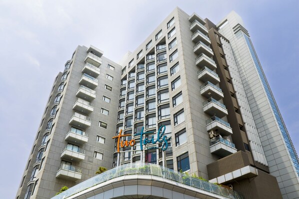 Un edificio moderno de gran altura con varios balcones y un pasillo de vidrio curvo.
