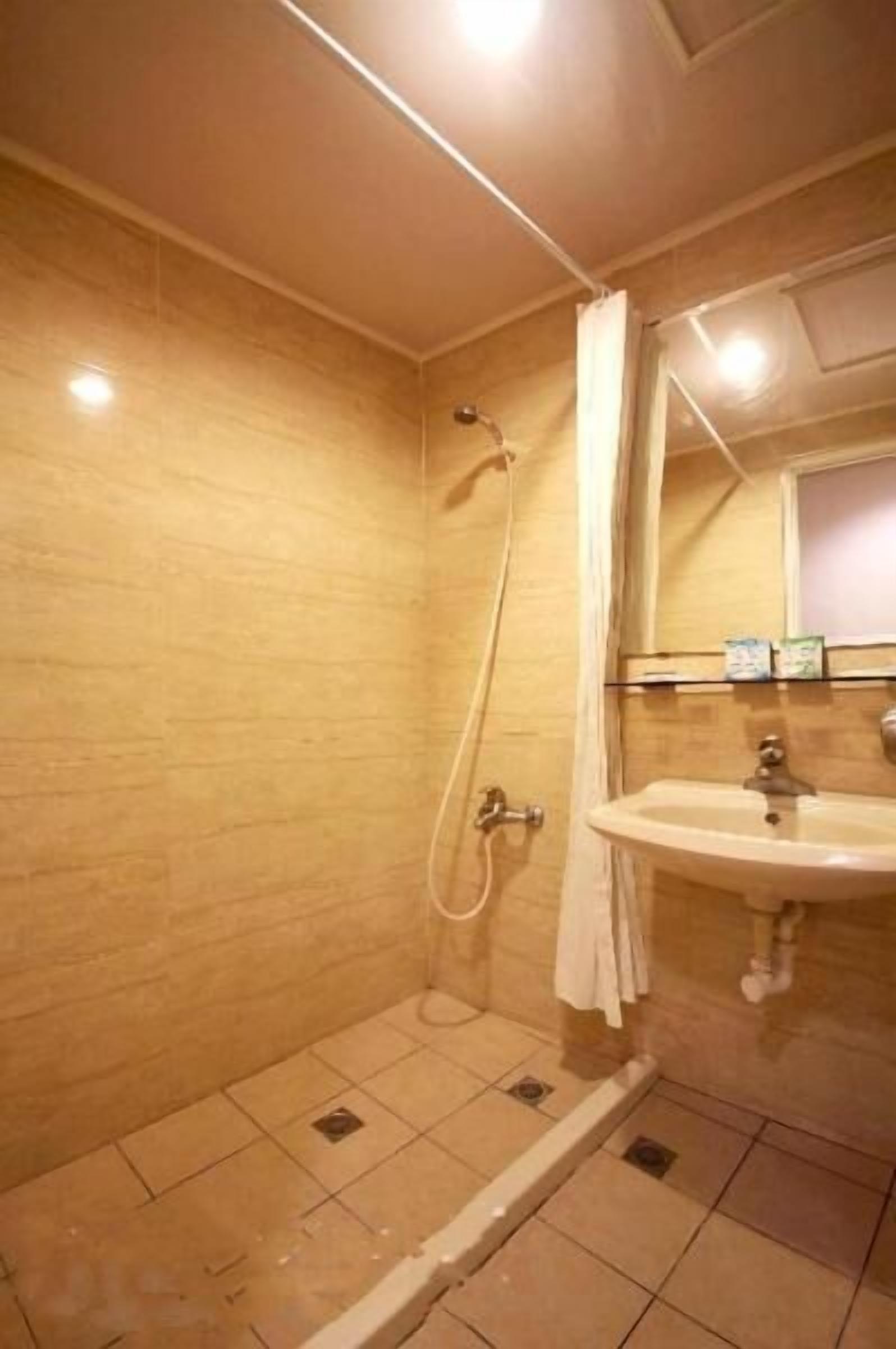 A small bathroom with a shower, a sink, and a mirror.