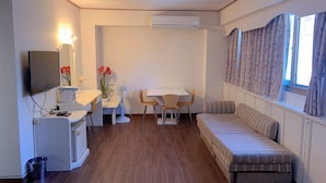 A compact living space with a kitchenette, a dining area, a sofa, and a TV mounted on the wall. - Traveler Hotel (Taitung)