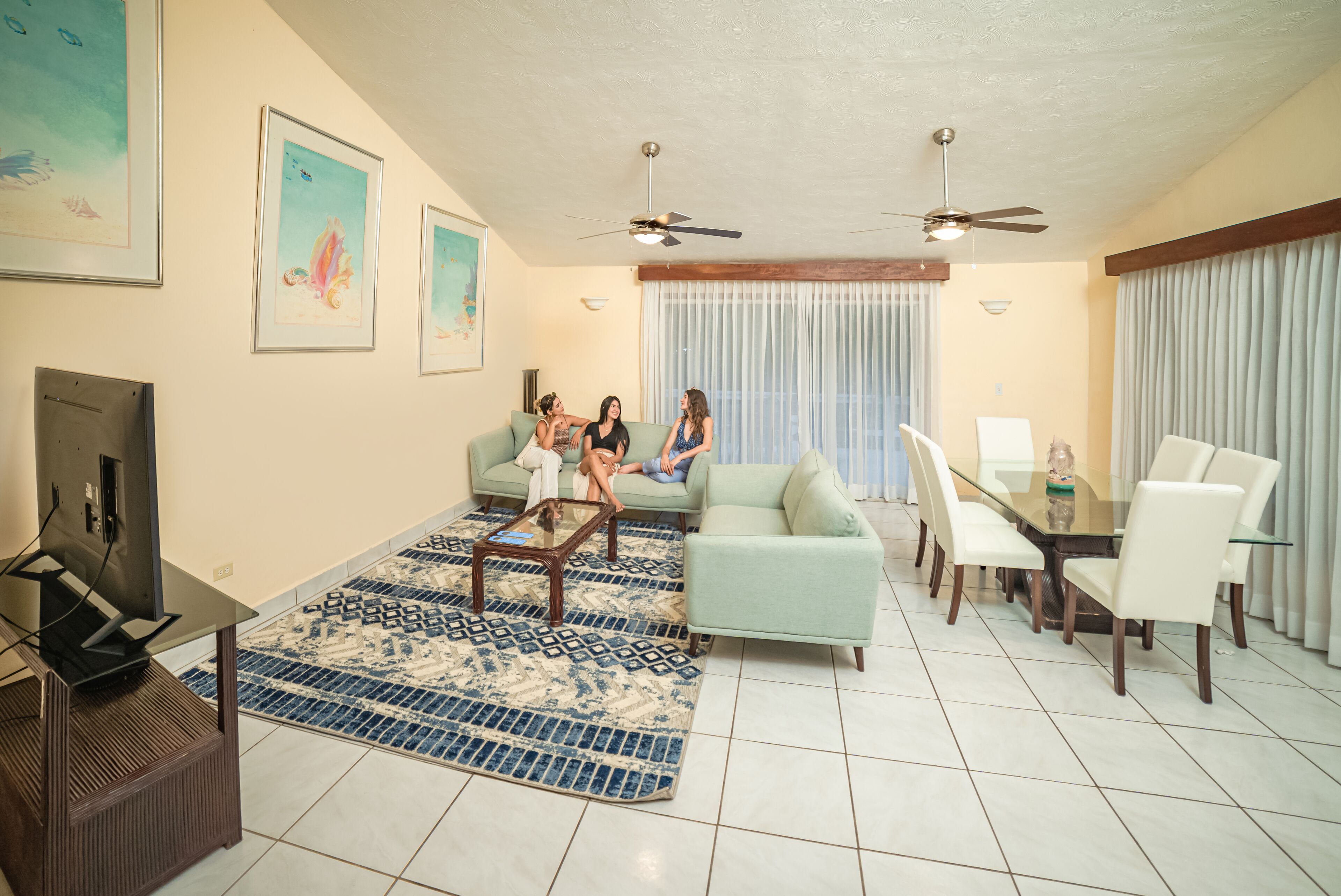 Un salon comprenant un canapé, une table basse, un téléviseur et un coin repas avec des chaises et une table.