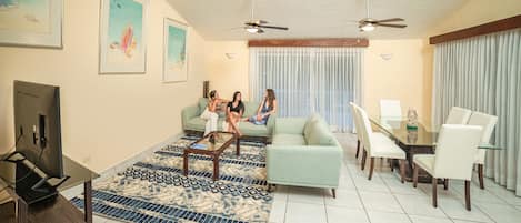 Un salon comprenant un canapé, une table basse, un téléviseur et un coin repas avec des chaises et une table.
