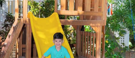 Una estructura de juego de madera con un tobogán amarillo.