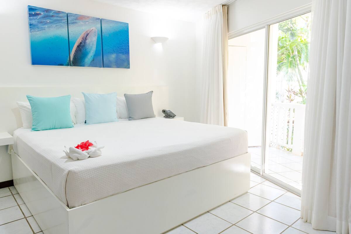 Habitación de hotel con una cama grande, un cuadro de una ballena, un teléfono y vistas al exterior.