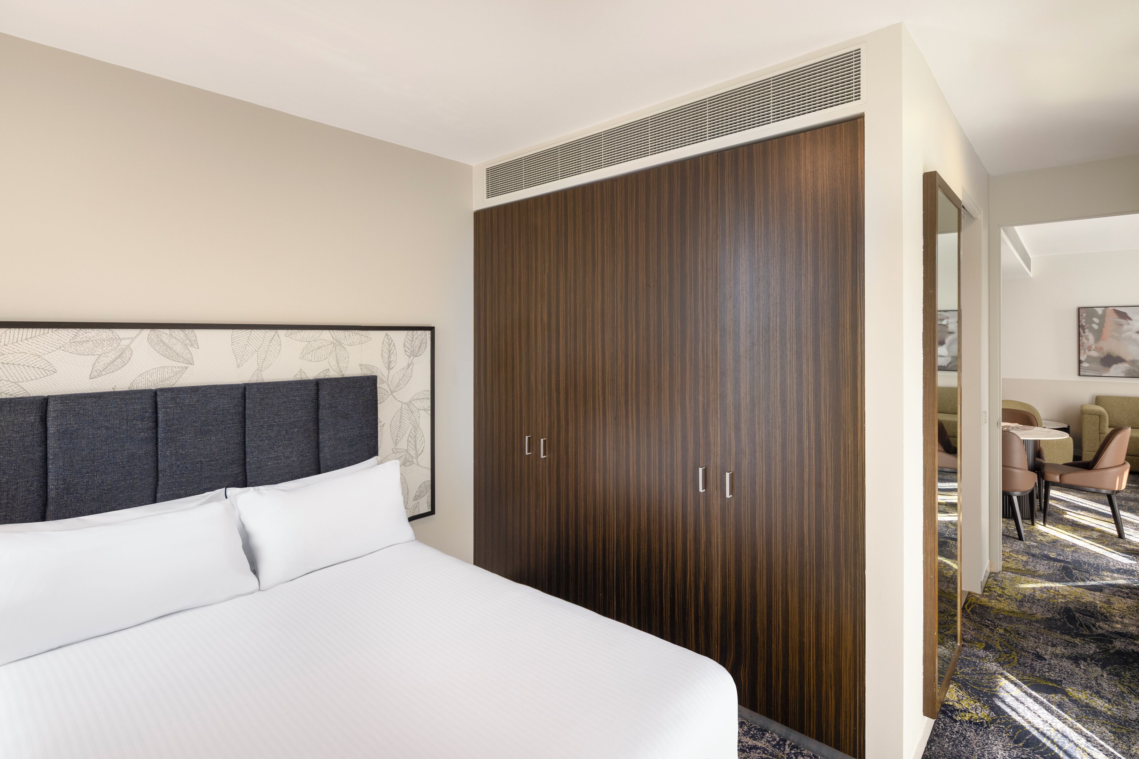 A hotel room with a large bed, a wardrobe, and a seating area with a table and chairs.