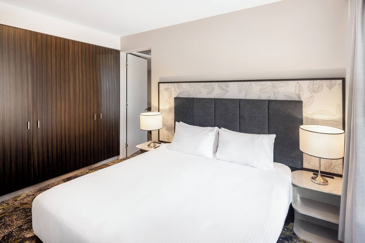 Una habitación de hotel con una cama grande, un armario y dos lámparas de noche.