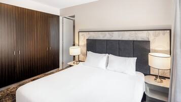 Una habitación de hotel con una cama grande, un armario y dos lámparas de noche.